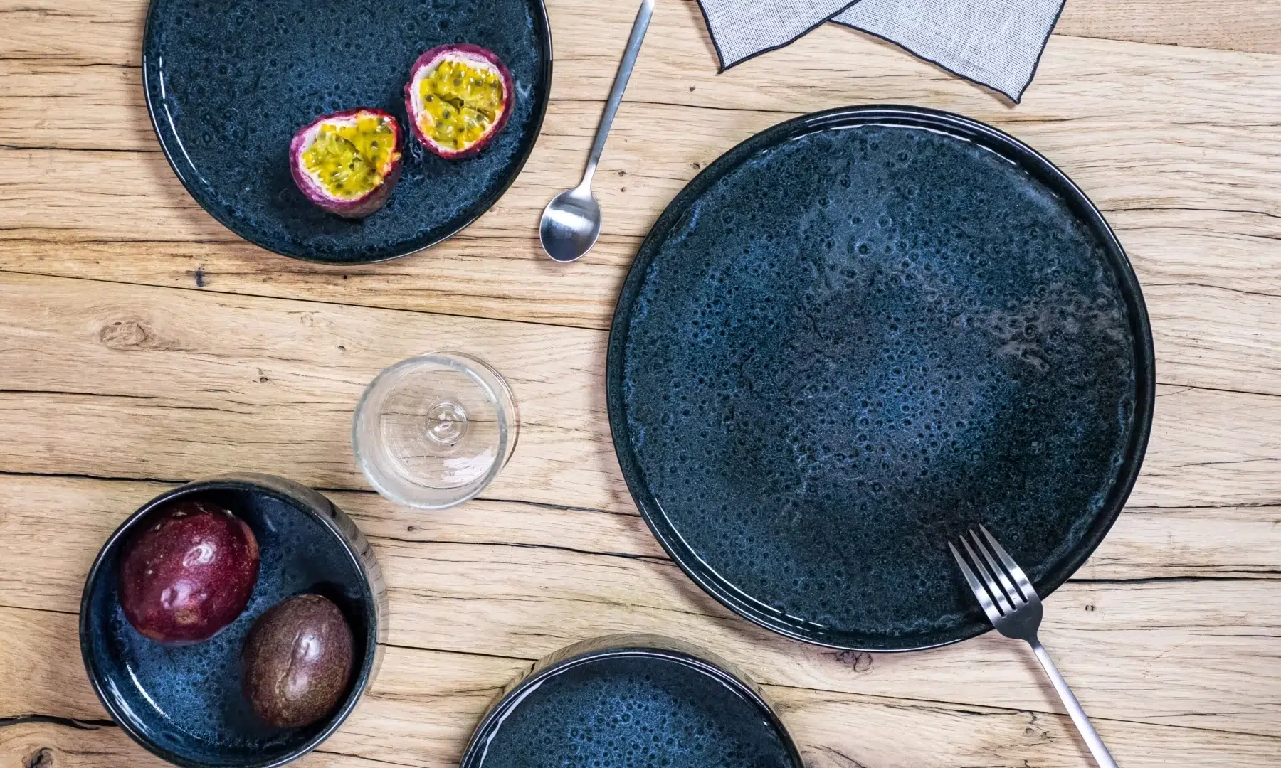 Assiettes bleus foncées couvert et verre dressés sur table en bois